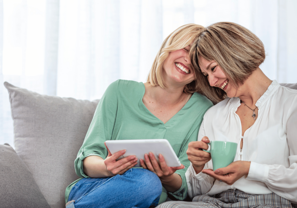 A woman and her mother laughing over something on the iPad