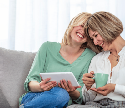 A woman and her mother laughing over something on the iPad