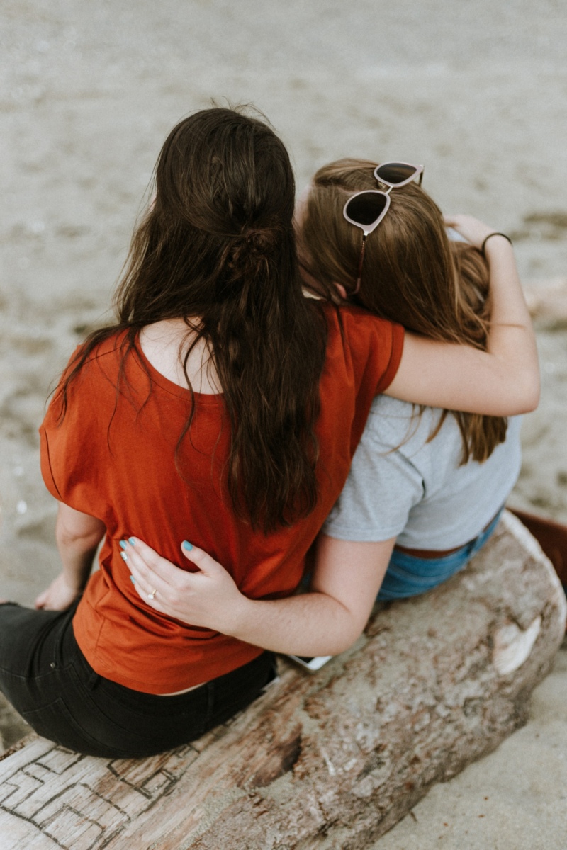 Two friends on beach arm on shoulder