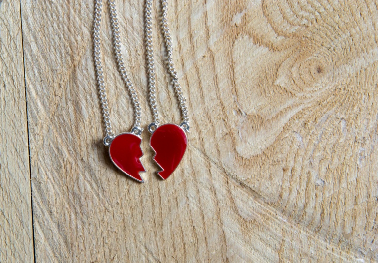 Broken red heart necklace on wooden background