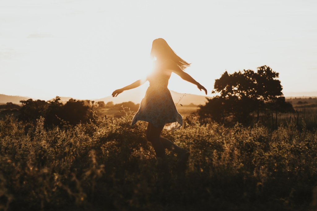 Woman walking outside with sun behind her