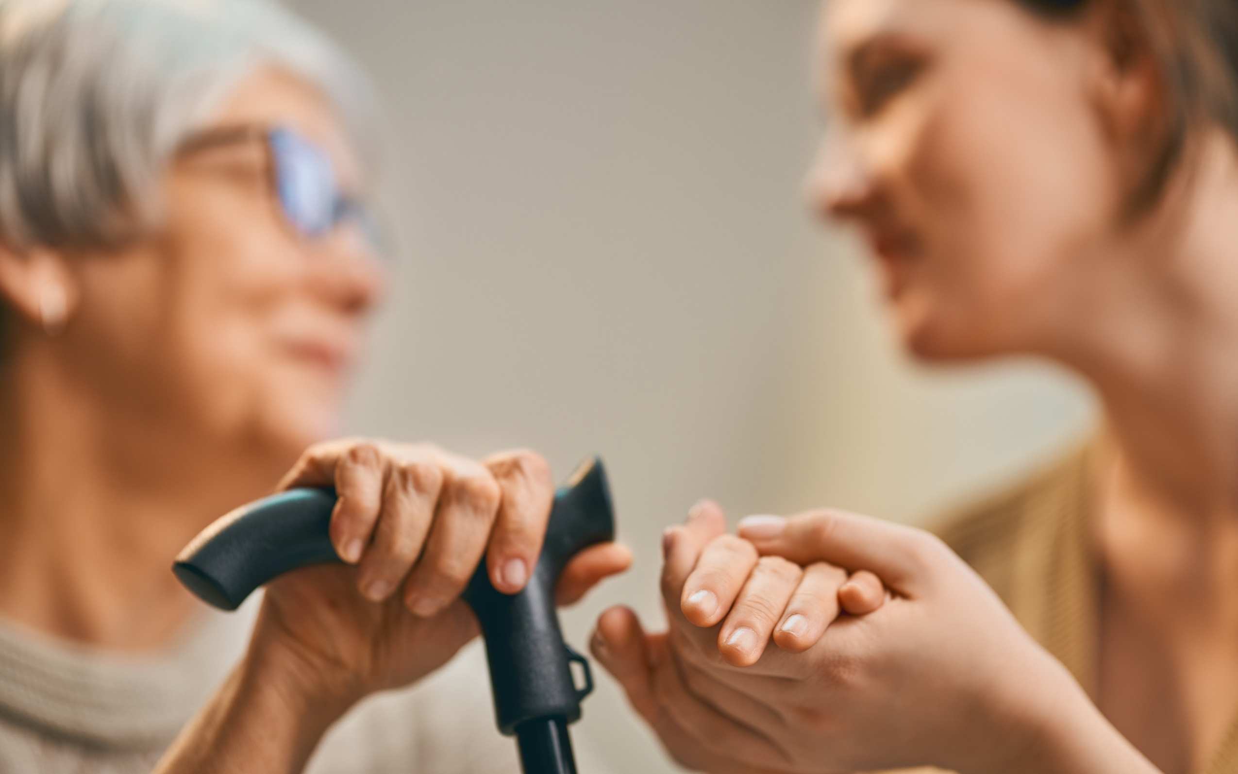caregiver holding hands with elderly woman