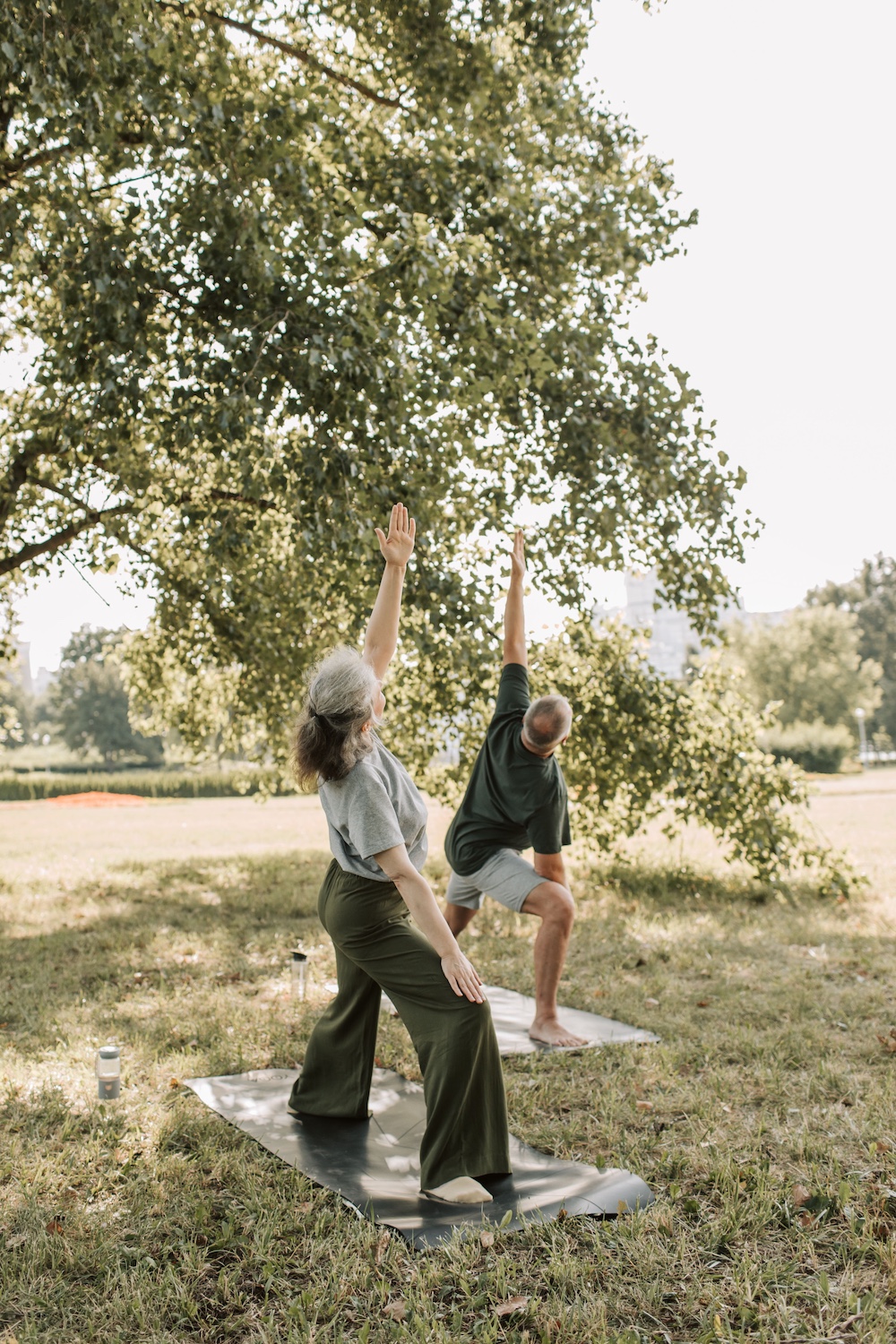 2 people doing yoga under a tree