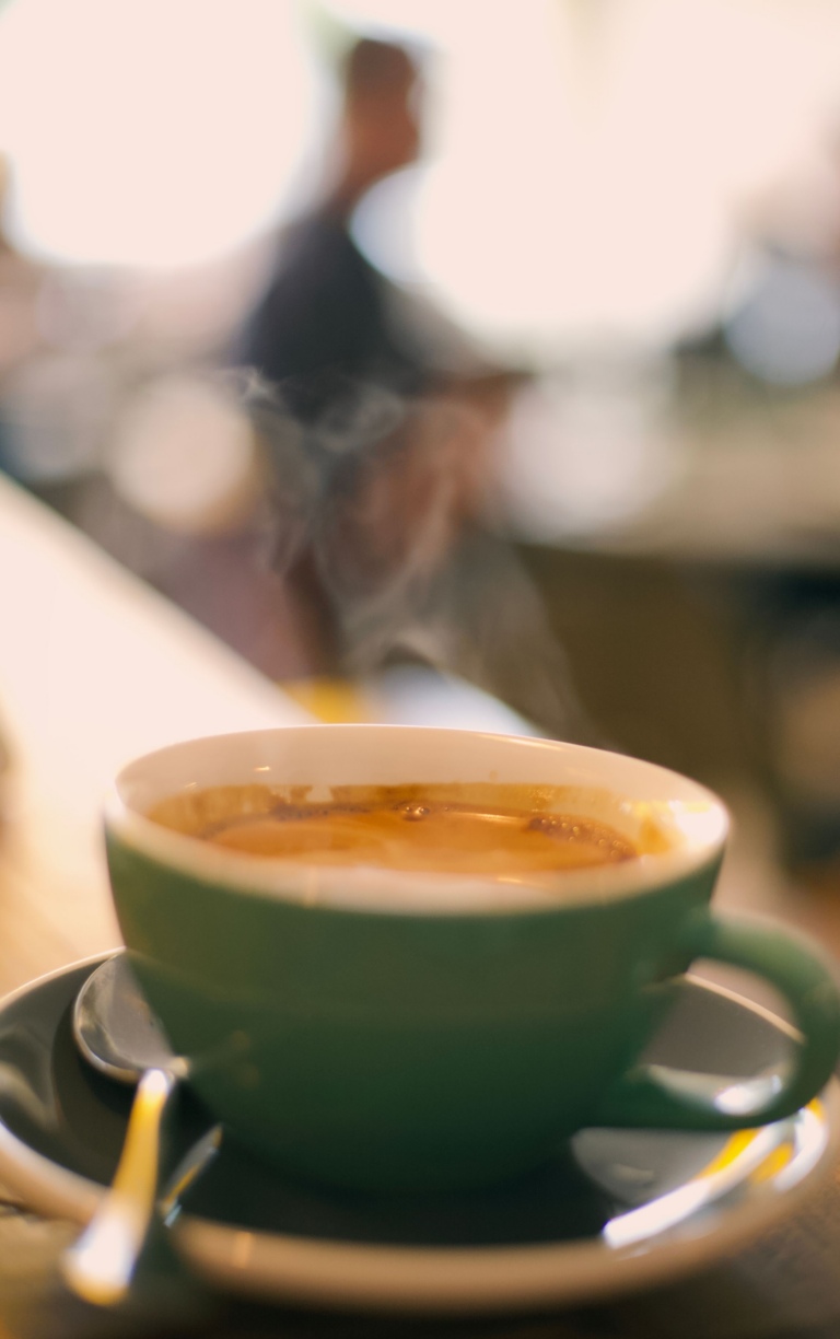 Green coffee cup with hot barista coffee in cafe